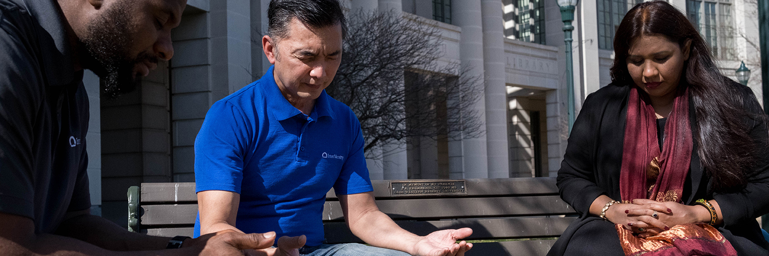 members pray on bench outdoors