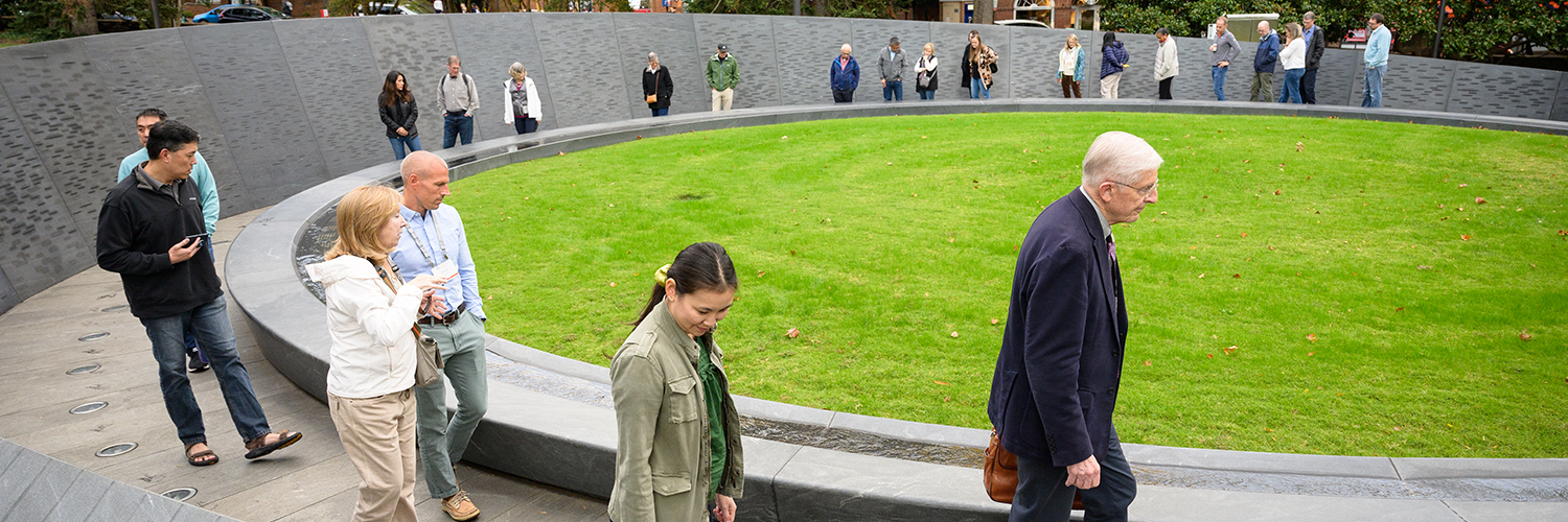 people walk around circular memorial