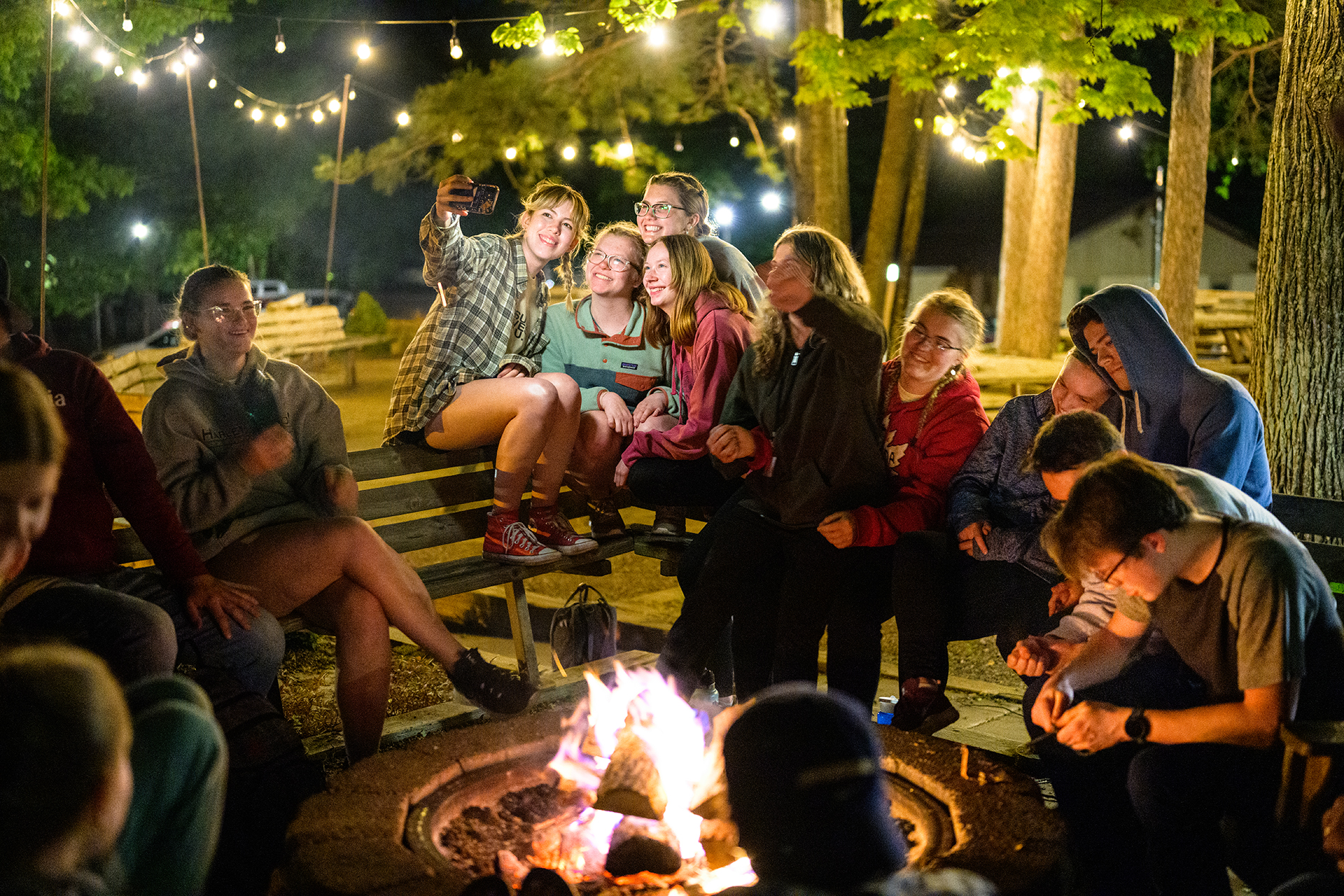 a group of students gather around a campfire.